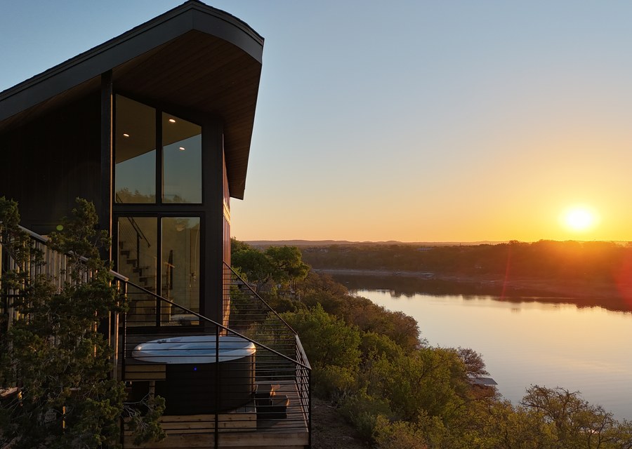 A modern cabin overlooking a lake at sunset
